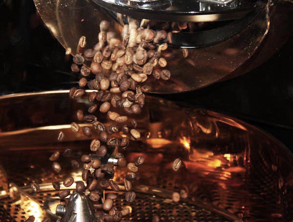 Hot, roasted coffee pouring out of the copper roaster